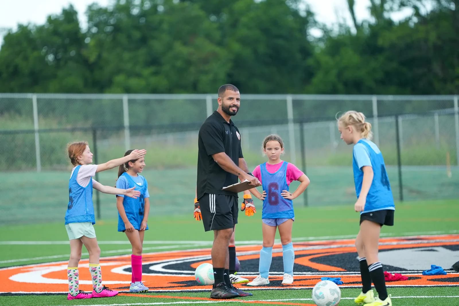 An ASC coach sharing smiles with his young Little Aledos players between drills at The Stable