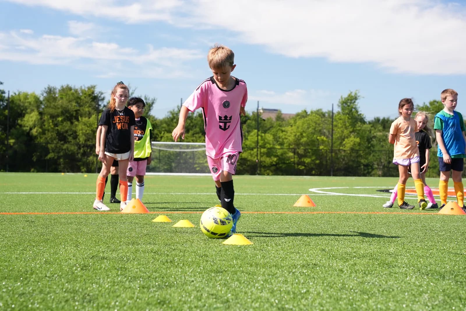 Little Aledos players taking turns dribbling through cones during training at The Stable